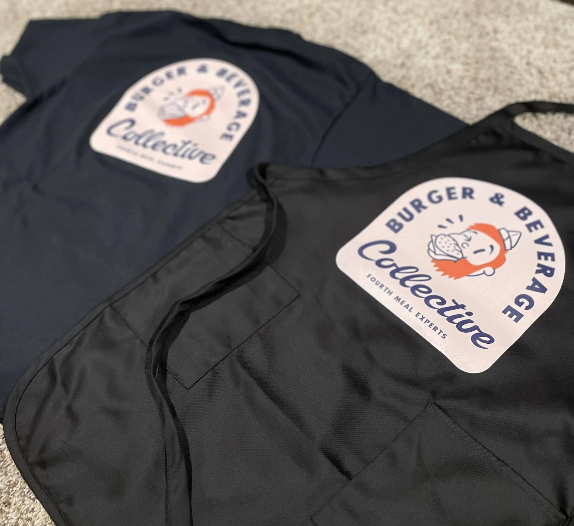 Burger & Beverage Collective navy tee and black apron with mascot logo